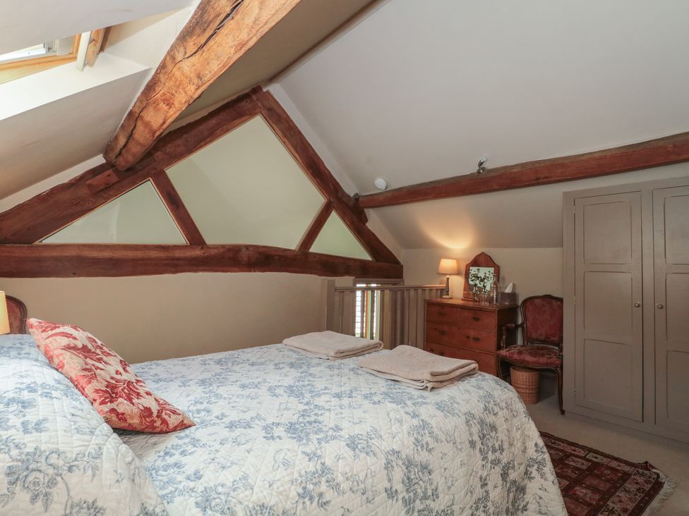 A bedroom with a bed and dresser at The Lodge Farm Barn Deepdean near Ross-on-Wye