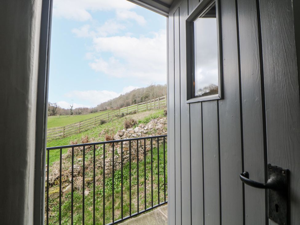 A view from a door showing a field with a fence and trees at Little Mill