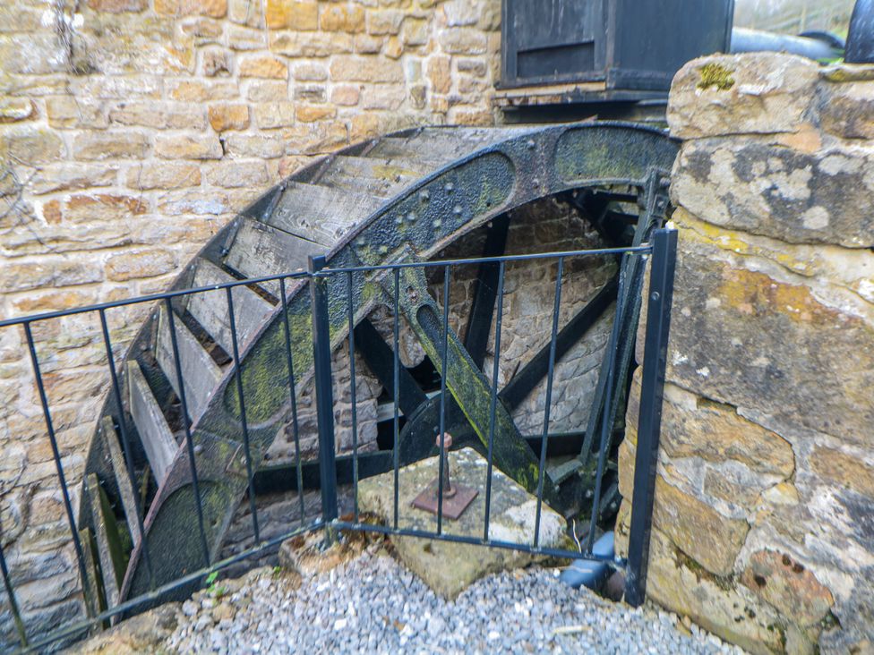 A water wheel structure next to a stone wall at Little Mill in 