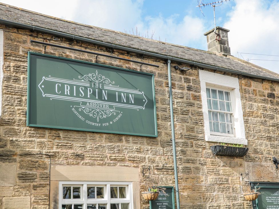 A pub sign on a stone building at The Crispin Inn in Ashover