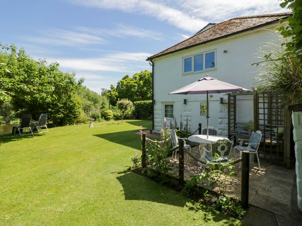 A garden with a table and chairs under an umbrella at Severn Bank Lodge in Astley Burf near Stourport-on-Severn