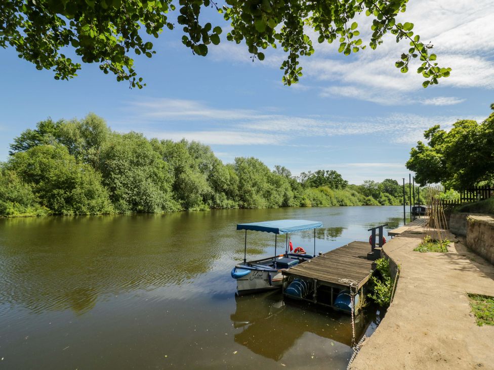 A river with a boat at a dock surrounded by trees at Severn Bank Lodge Astley Burf near Stourport-on-Severn