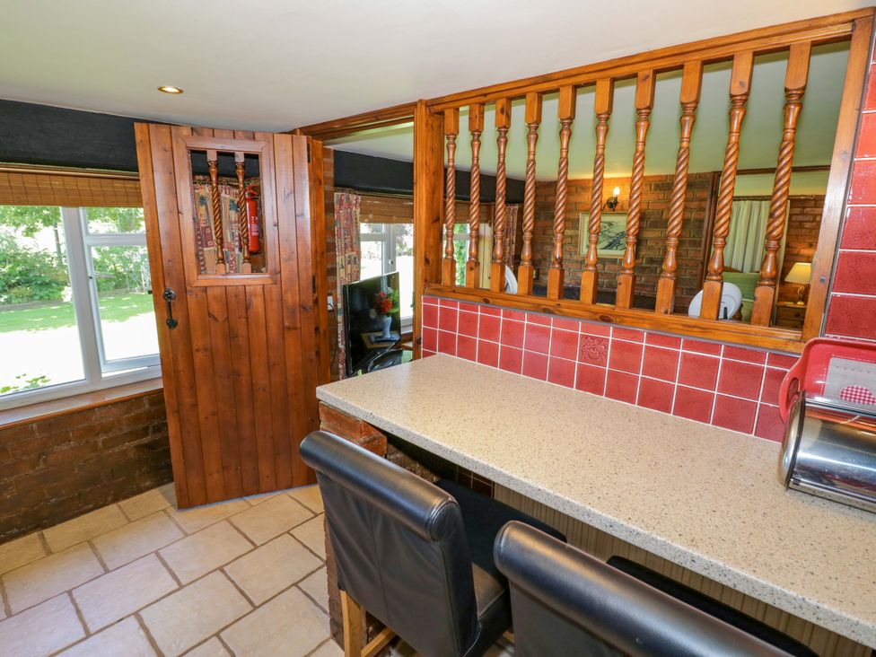 A kitchen with a serving window and bar stools at Severn Bank Lodge Astley Burf near Stourport-on-Severn