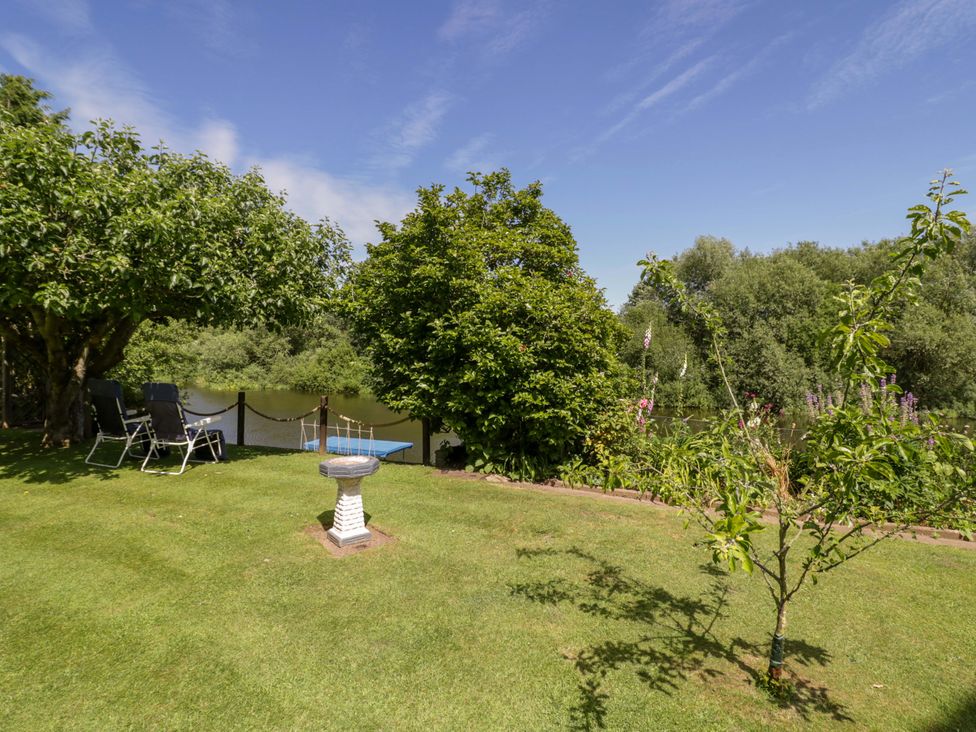 A garden with a bird bath and deck chairs at Severn Bank Lodge in Astley Burf near Stourport-on-Severn