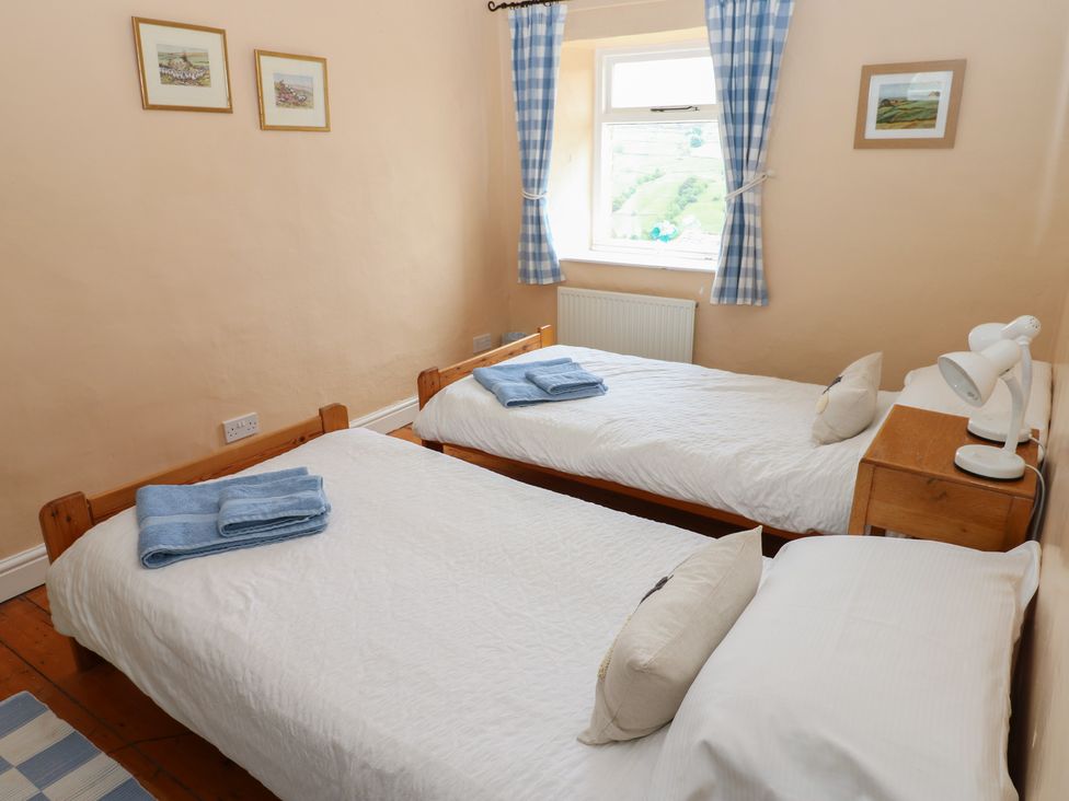 A bedroom with two single beds and a nightstand at High Smarber in Low Row near Reeth