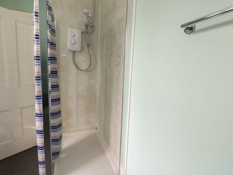 A shower with a curtain and shower head at Halford Hill Llanberis