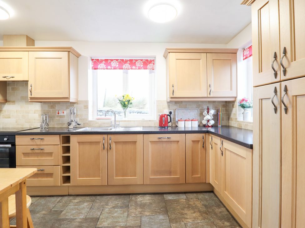 A kitchen with cabinets, sink, kettle, and window at Bryn Re, Trawsfynydd near Llan Ffestiniog and Dolgellau