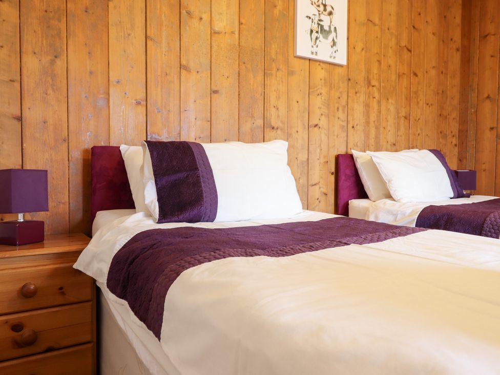 A bedroom with two beds and a lamp on a nightstand at Bryn Re Trawsfynydd near Llan Ffestiniog and Dolgellau