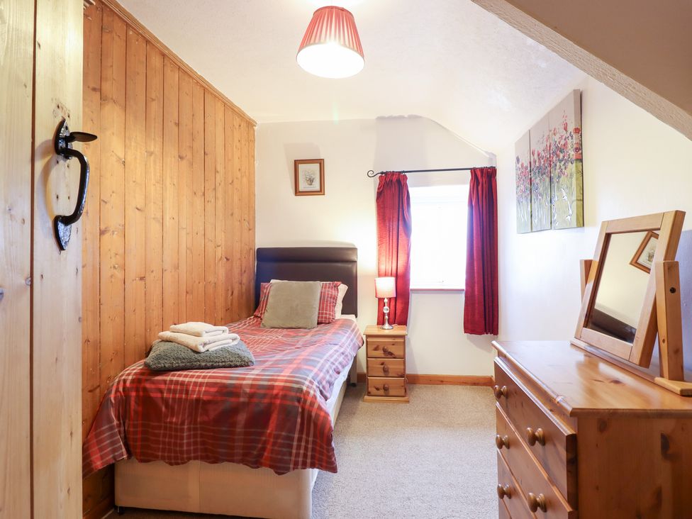 A bedroom featuring a single bed, dresser, and window at Bryn Re Trawsfynydd near Llan Ffestiniog and Dolgellau