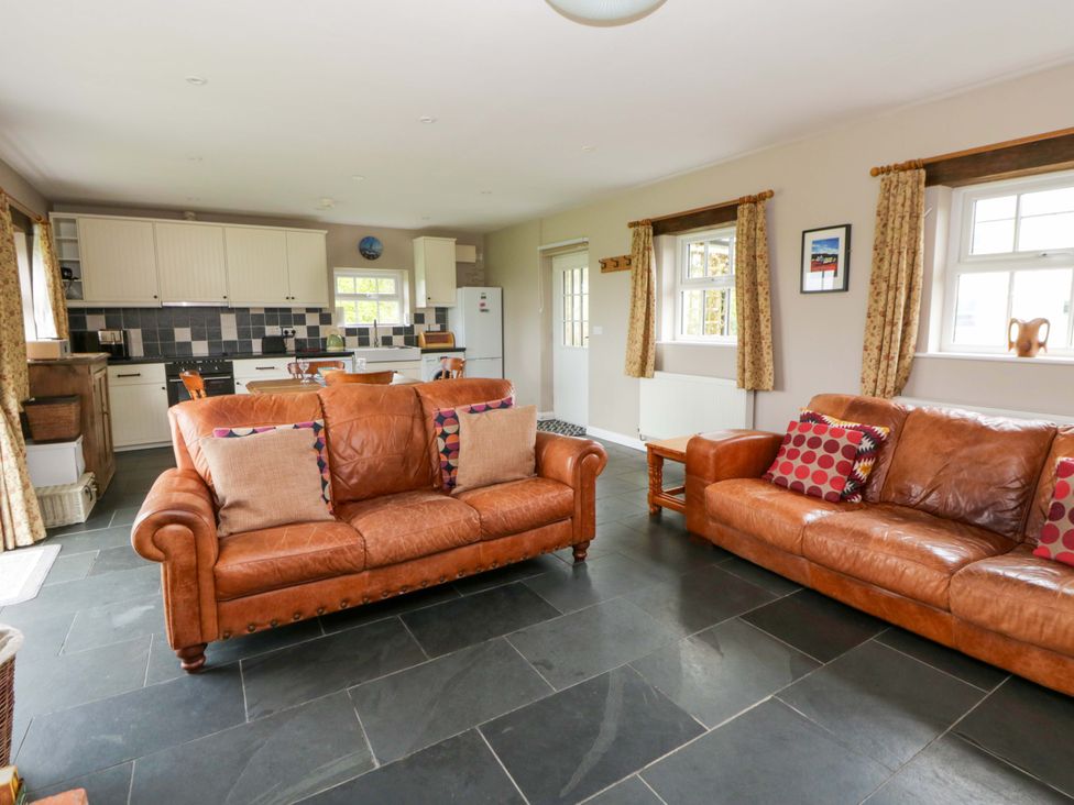 A living room with sofa and kitchen in the background at Blaenffynnon Bach in Trelech near Crymych