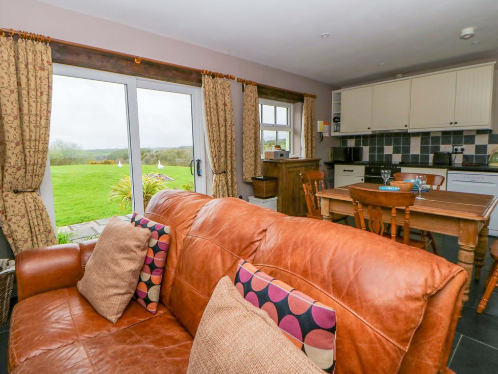 A living room with a sofa and dining area at Blaenffynnon Bach in Trelech near Crymych