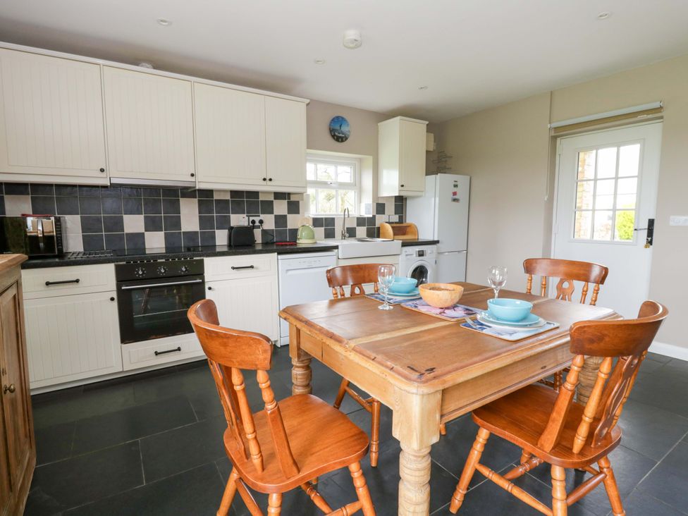 A kitchen with a dining table and appliances at Blaenffynnon Bach in Trelech near Crymych