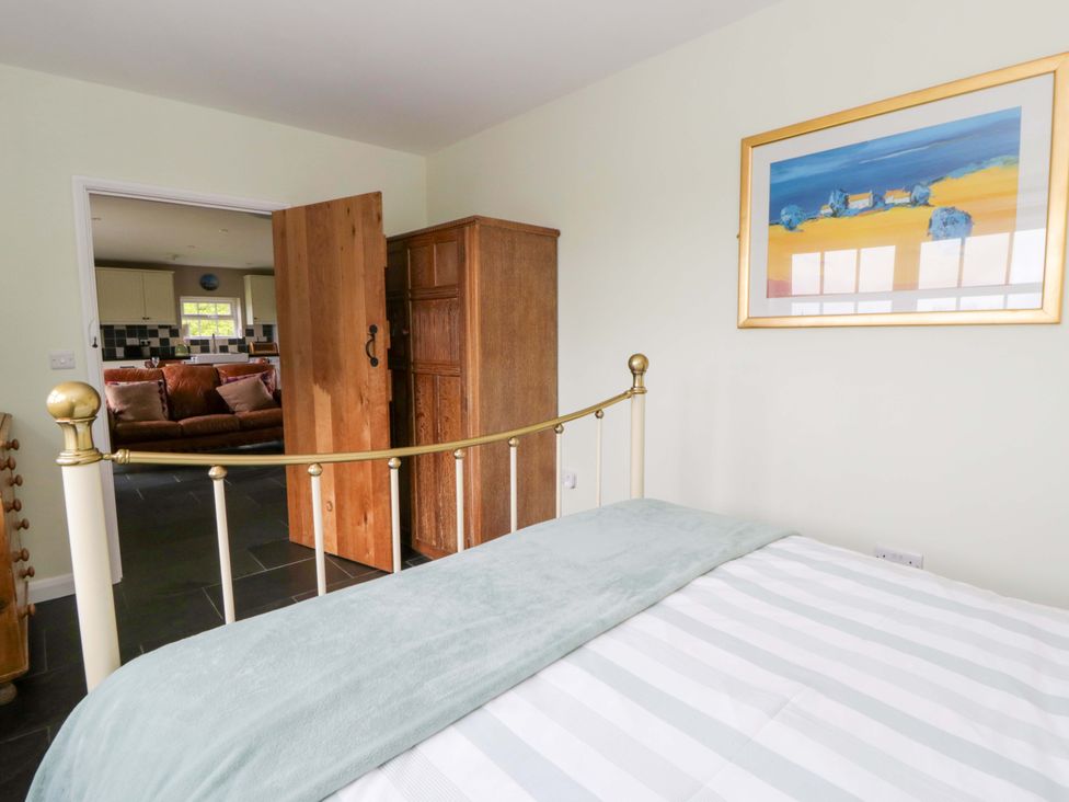 A bedroom with a bed and an open door leading to another room at Blaenffynnon Bach in Trelech near Crymych