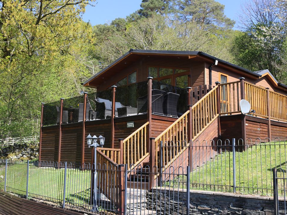 A wooden lodge with a deck and stairs at High View Lodge White Cross Bay near Troutbeck Bridge