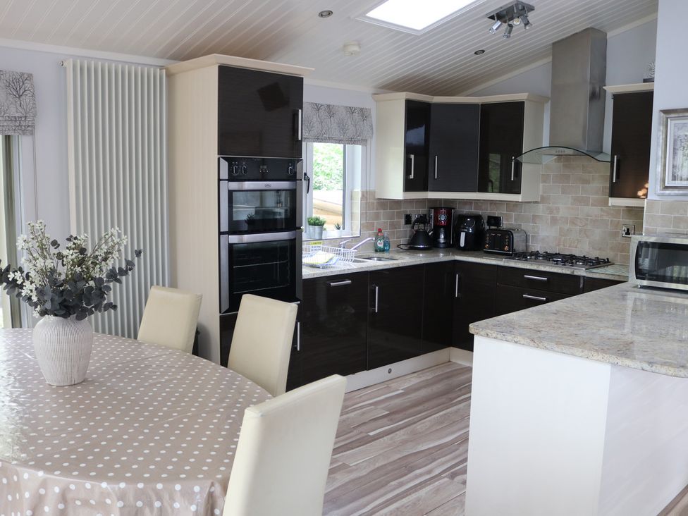 A kitchen with an oven, sink, and table at High View Lodge near Troutbeck Bridge