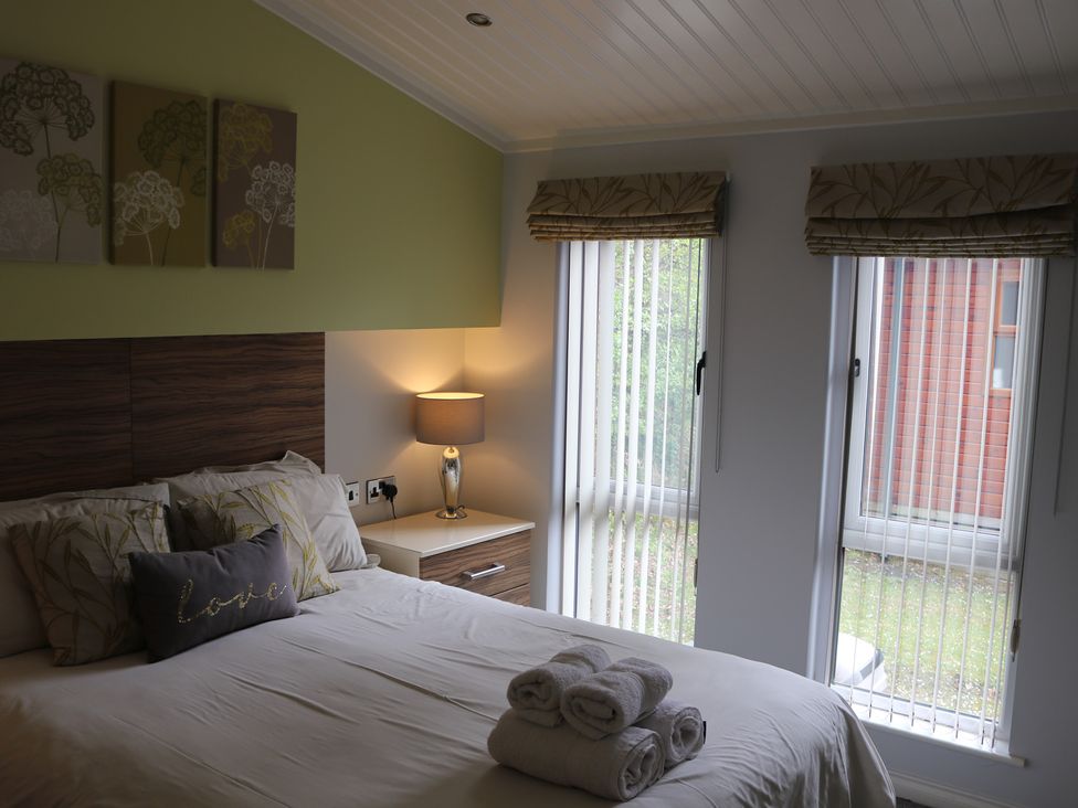 A bedroom with a bed and bedside table at High View Lodge near Troutbeck Bridge