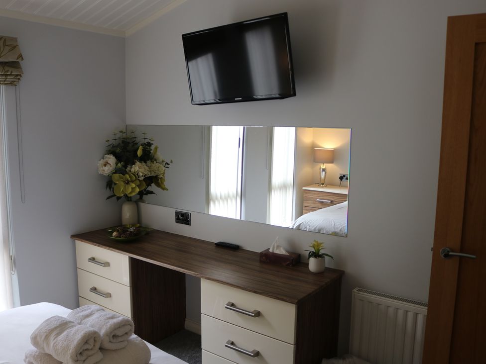 A bedroom with a dresser and television at High View Lodge near Troutbeck Bridge