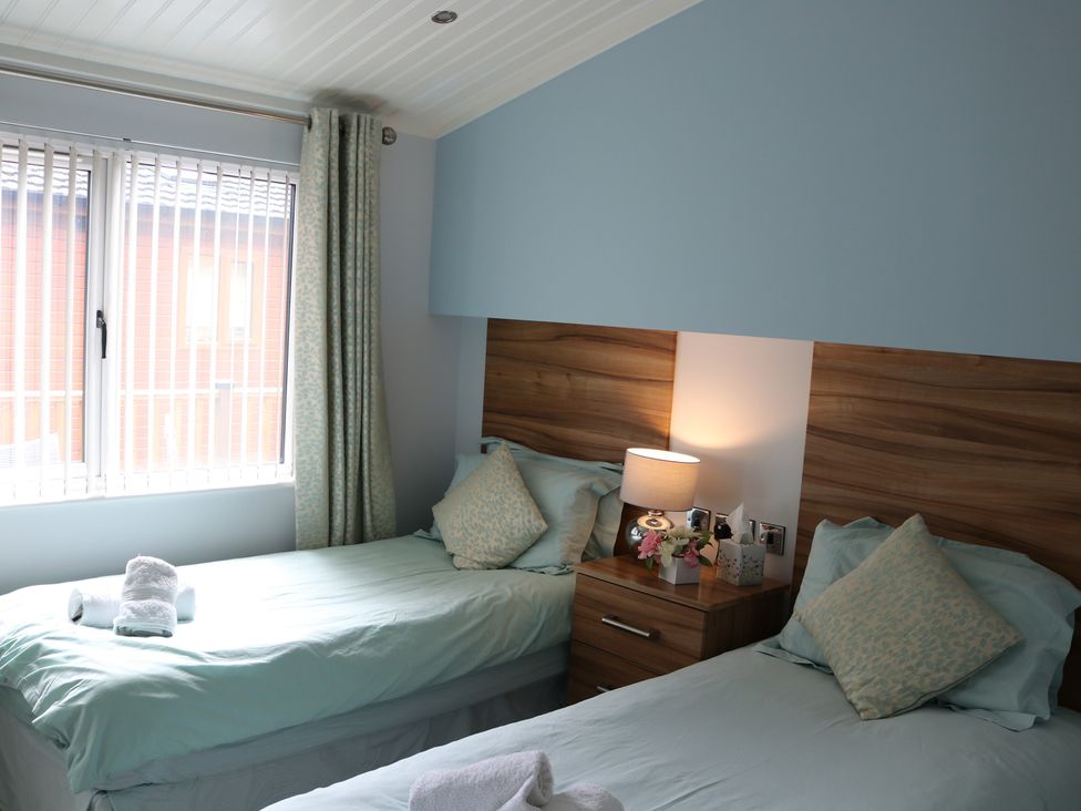 A bedroom with two single beds and a window at High View Lodge White Cross Bay near Troutbeck Bridge