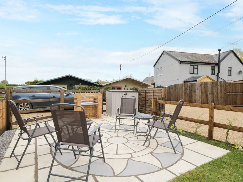 A garden patio with chairs and a car at The Nook in Royal Wootton Bassett