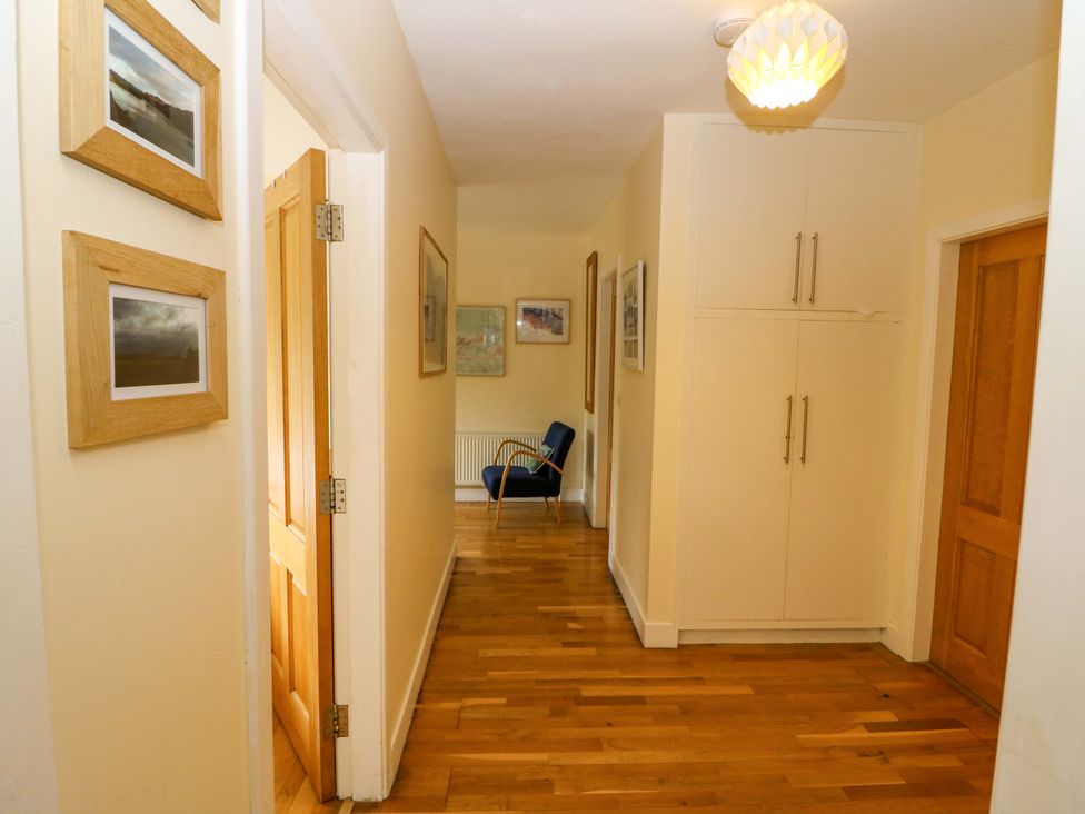 A hallway with a chair and pictures on the wall at Rowantree in Beaufort, County Kerry