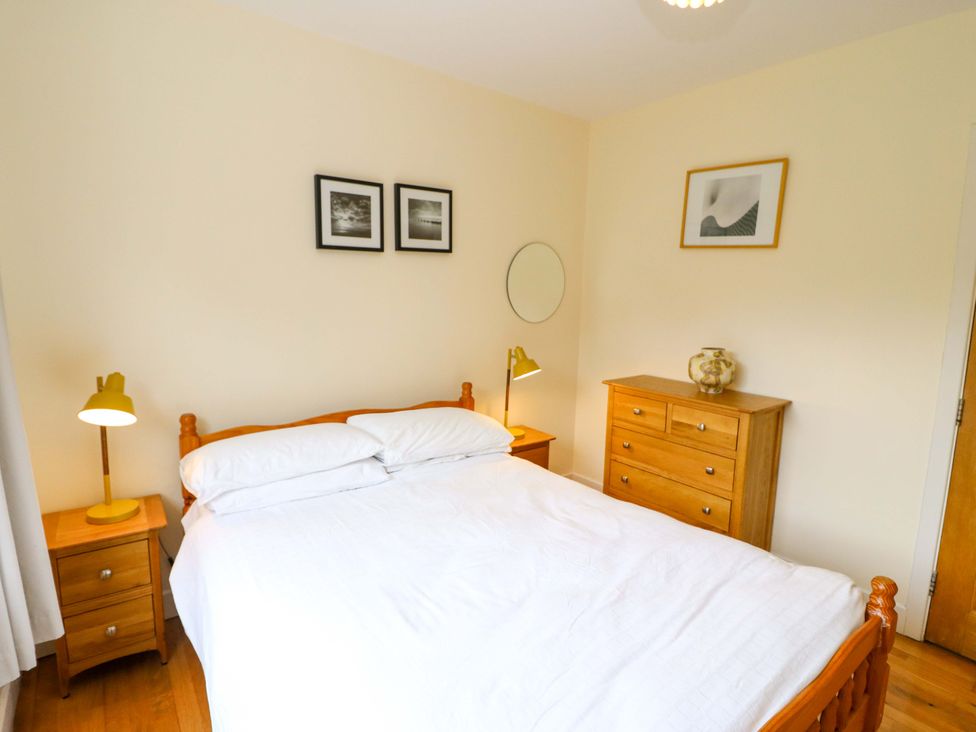 A bedroom with a bed, dresser and lamp at Rowantree in Beaufort, County Kerry