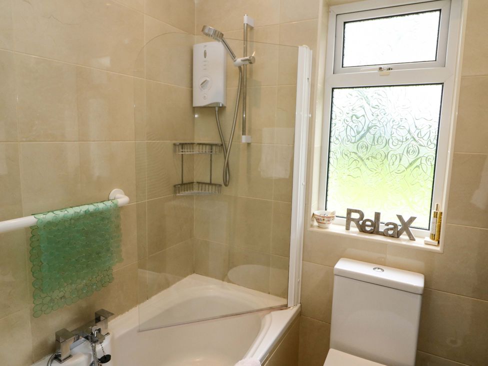 A bathroom featuring a bathtub with shower, toilet, and window at Rowantree, Beaufort, County Kerry