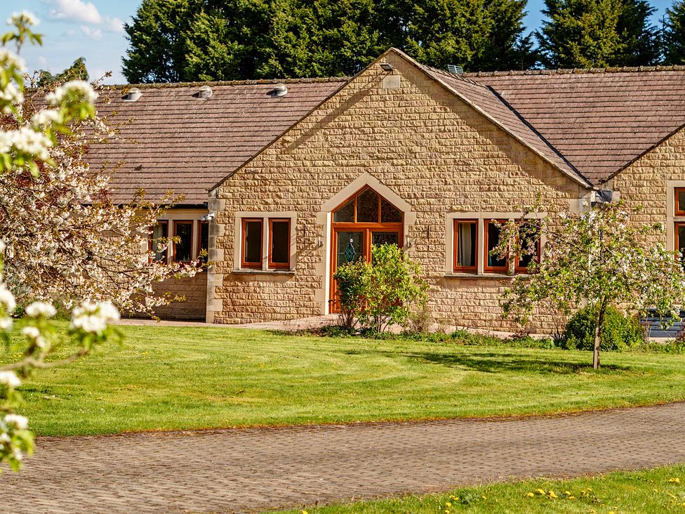 A stone house with windows and door surrounded by grass and trees at Manor House in Chesterfield