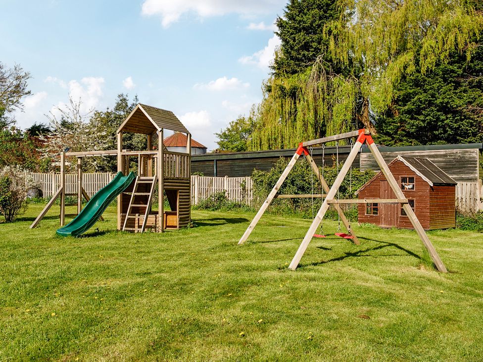 A playground structure with a slide and swing set in a garden at Manor House in Chesterfield