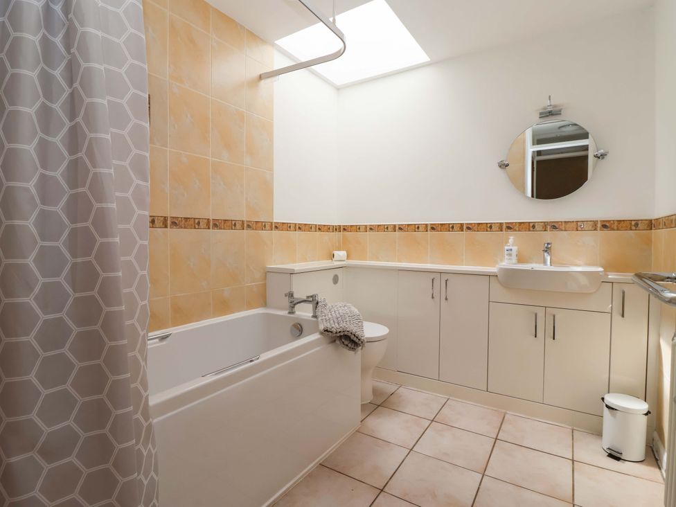 A bathroom with a bathtub, toilet, sink, and mirror at The Milking Parlour in York