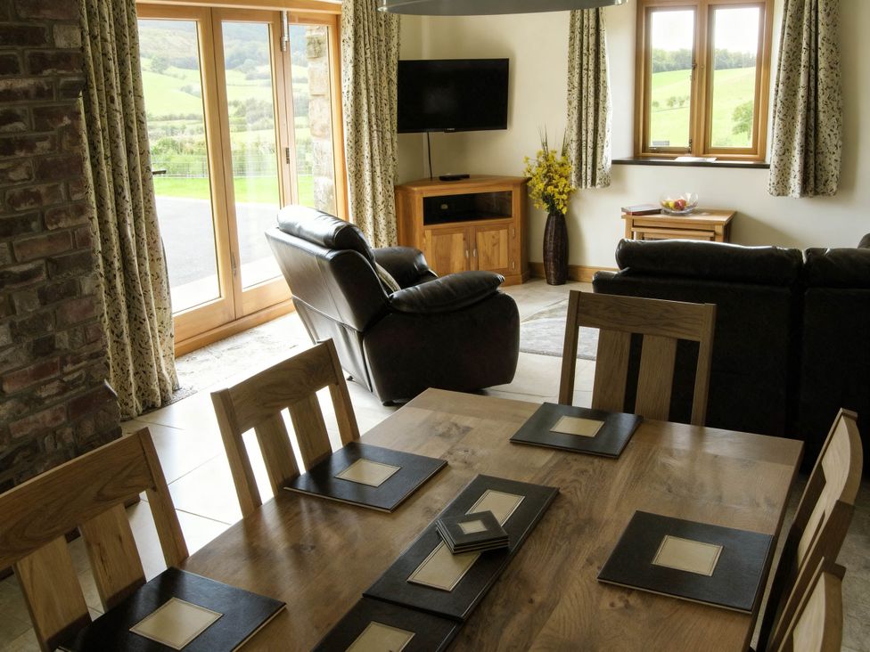 A living room with a sofa and dining area at Tyn Y Celyn Canol Clocaenog near Ruthin