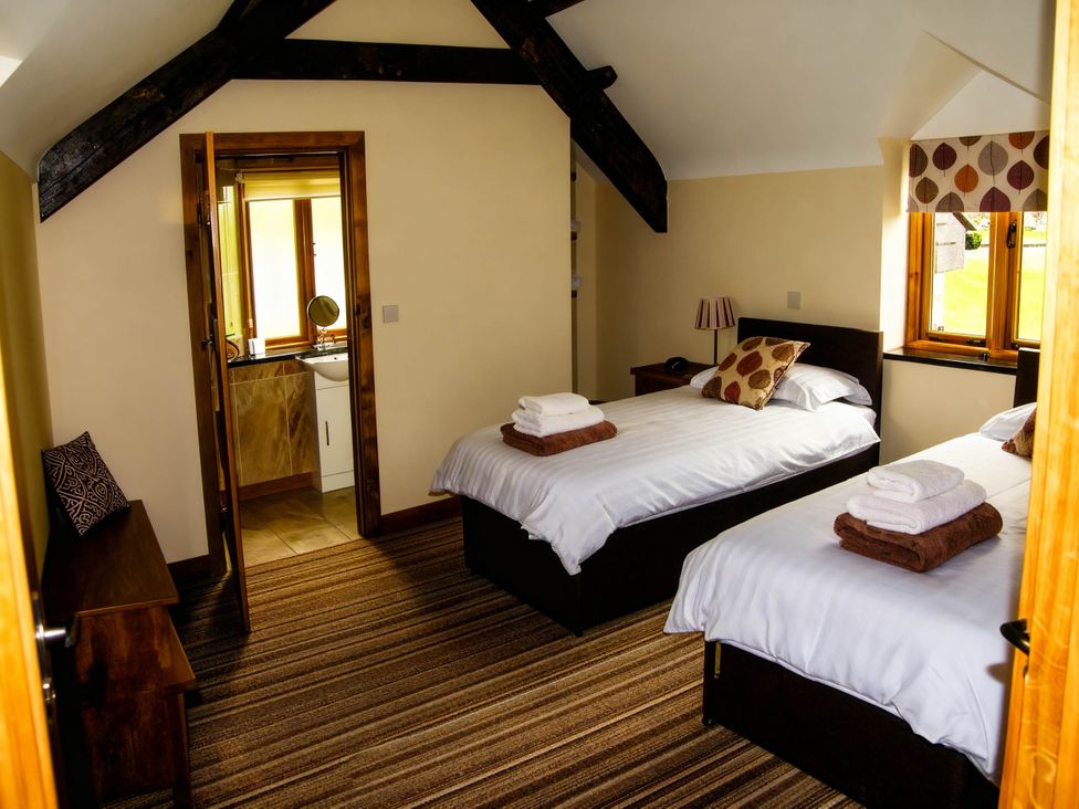 A bedroom with two beds and a bathroom at Tyn Y Celyn Canol Clocaenog near Ruthin