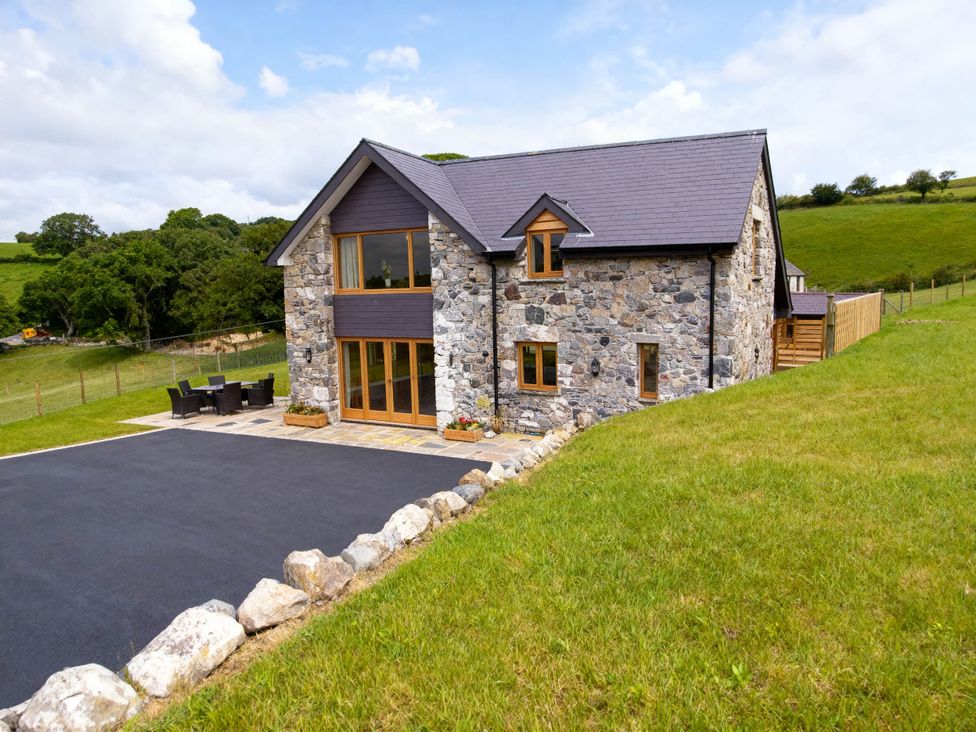A house with a stone exterior and outdoor dining area at Tyn Y Celyn Canol in Clocaenog near Ruthin