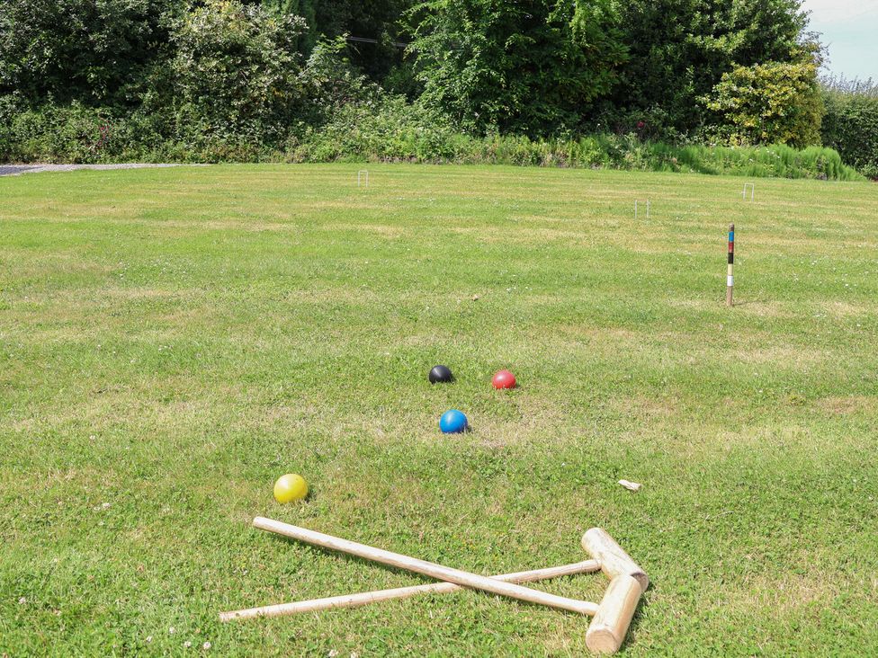 A croquet setup with colored balls and mallets in a grassy area at Butler's Flat in Cefn Park