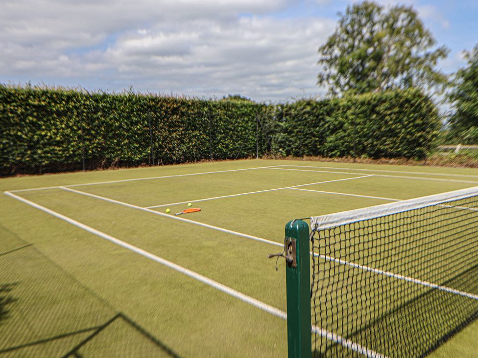 A tennis court with a racket and balls at Butler's Flat Cefn Park
