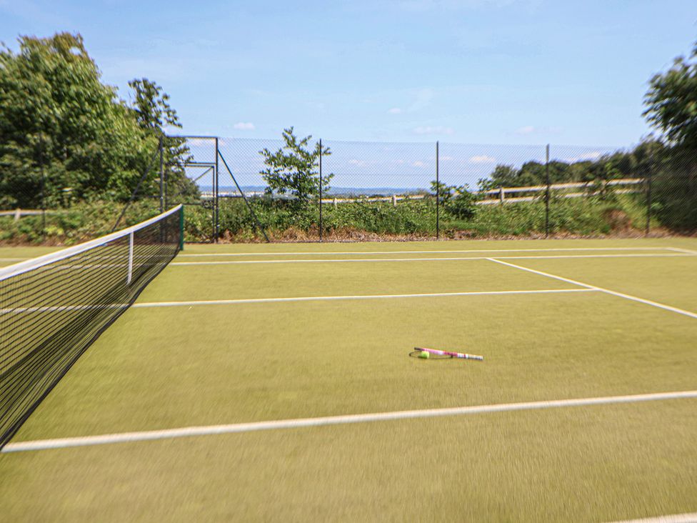 A tennis court with a racket and ball on the ground at Butler's Flat, Cefn Park