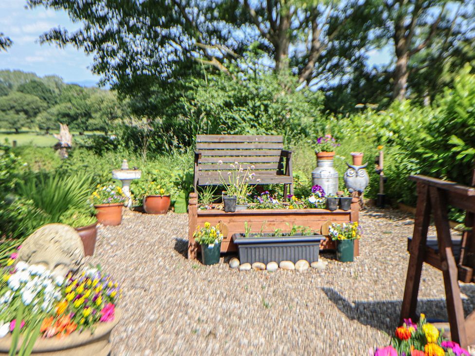 A garden with a wooden bench and flower pots at Butler's Flat Cefn Park