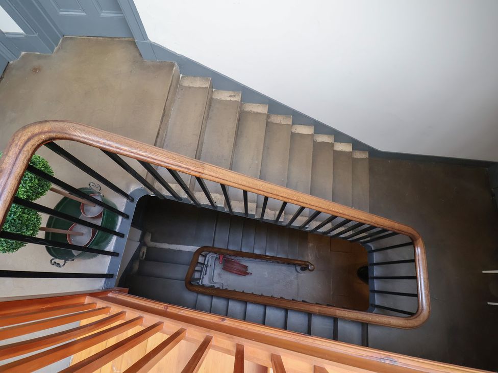 A staircase with wooden railing and green plants at Butler's Flat Cefn Park