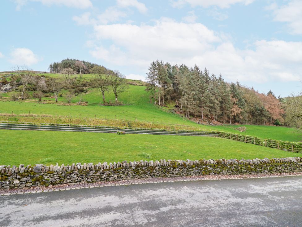 A view of a grassy hill with trees and a stone wall at Briws and 963354 together they sleep 35