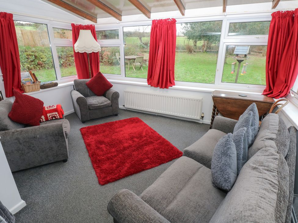 A conservatory with a sofa and armchair at Maesgwyn in Bridell near Cardigan