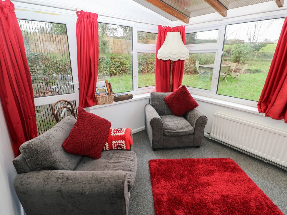 A conservatory with sofas and a lamp at Maesgwyn in Bridell near Cardigan