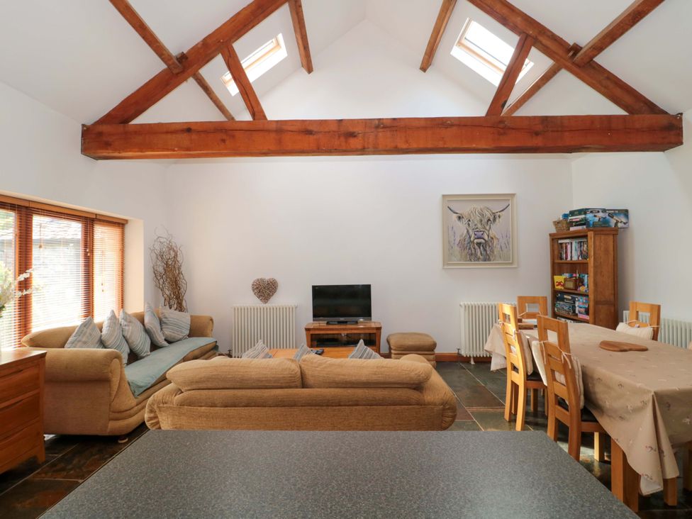 A living room with a sofa and dining area at Riverside Barn in Gilwern near Crickhowell and Abergavenny