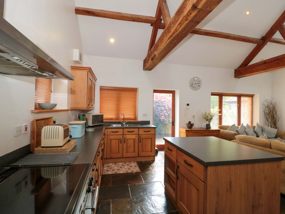 A kitchen with wooden cabinets and a dining area at Riverside Barn Gilwern near Crickhowell and Abergavenny