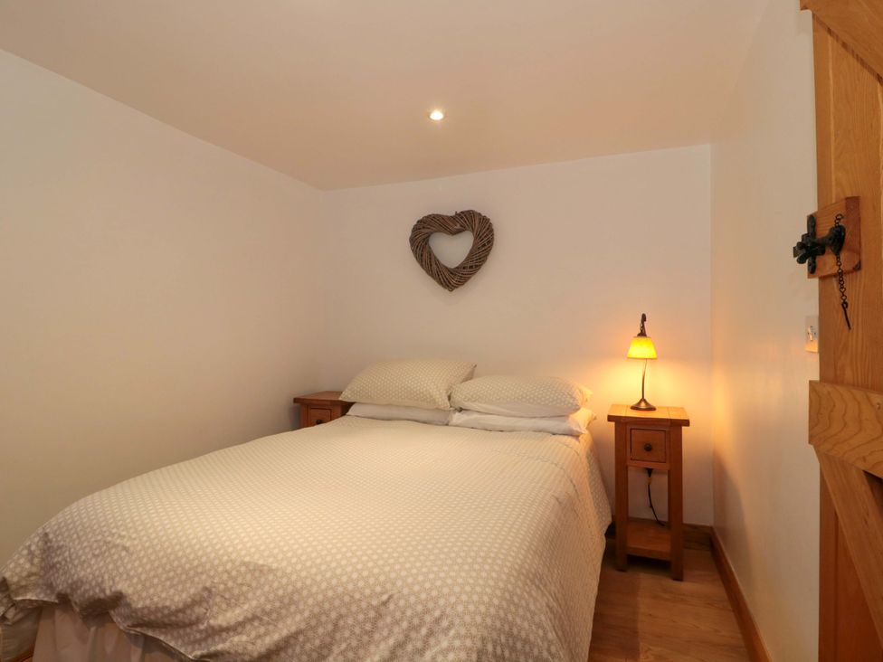 A bedroom with a bed and nightstand at Riverside Barn in Gilwern near Crickhowell and Abergavenny