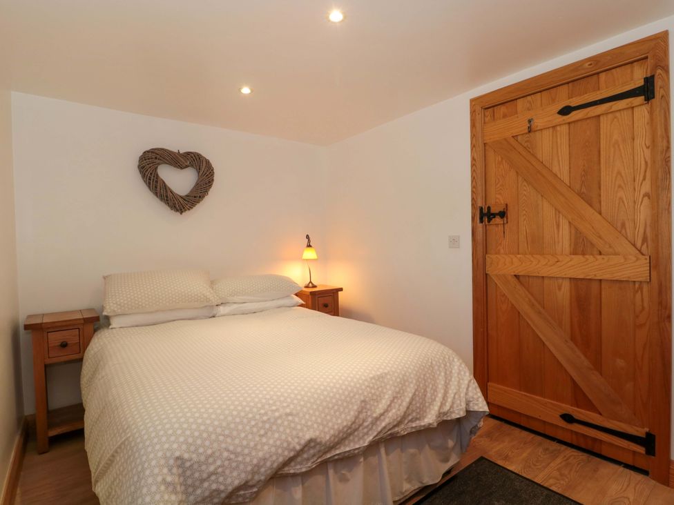 A bedroom with a bed and bedside table at Riverside Barn in Gilwern near Crickhowell and Abergavenny