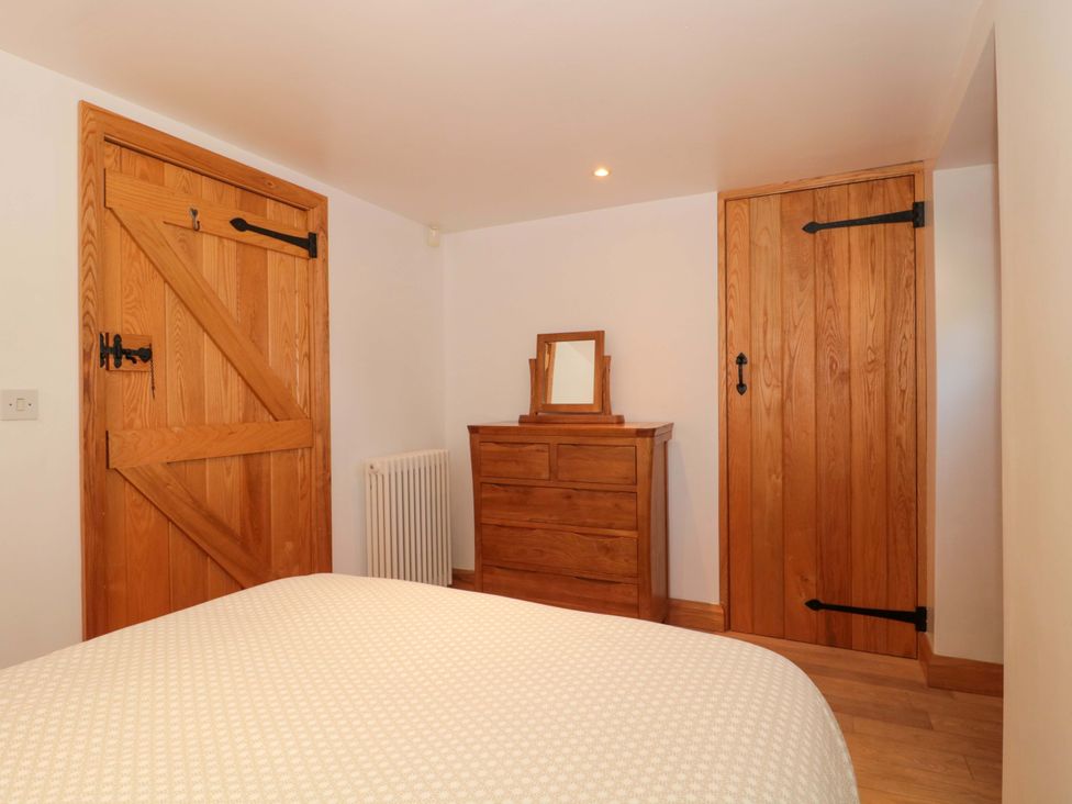 A bedroom with a bed and wooden furniture at Riverside Barn in Gilwern near Crickhowell and Abergavenny