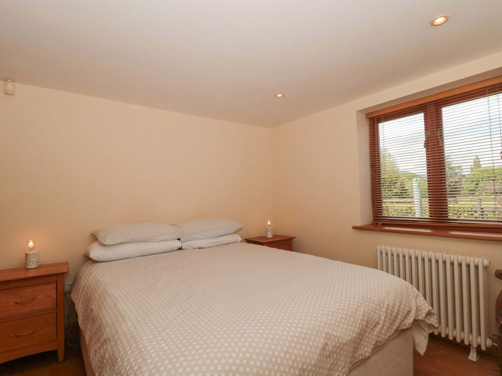 A bedroom with a bed and dresser at Riverside Barn in Gilwern near Crickhowell and Abergavenny