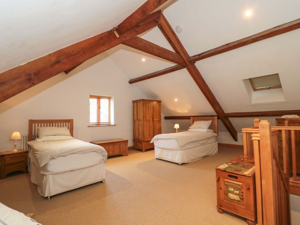 A bedroom with two beds and wooden furniture at Riverside Barn in Gilwern near Crickhowell and Abergavenny