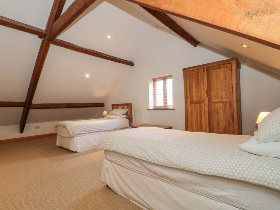 A bedroom with two beds and a wooden wardrobe at Riverside Barn in Gilwern near Crickhowell and Abergavenny
