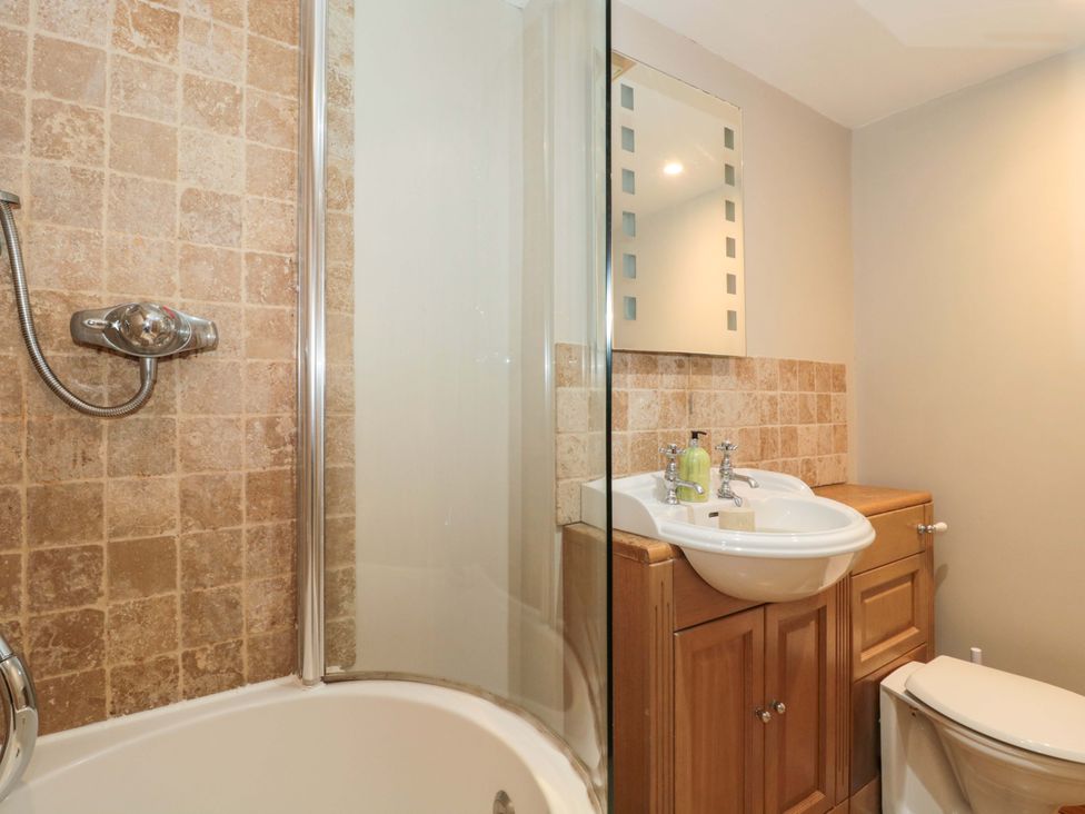 A bathroom with a shower, sink, toilet, and mirror at Riverside Barn in Gilwern near Crickhowell and Abergavenny