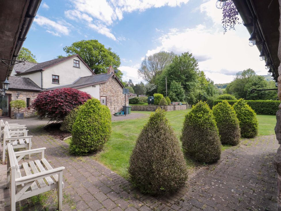 An outdoor garden area with hedges and chairs at Riverside Barn in Gilwern near Crickhowell and Abergavenny